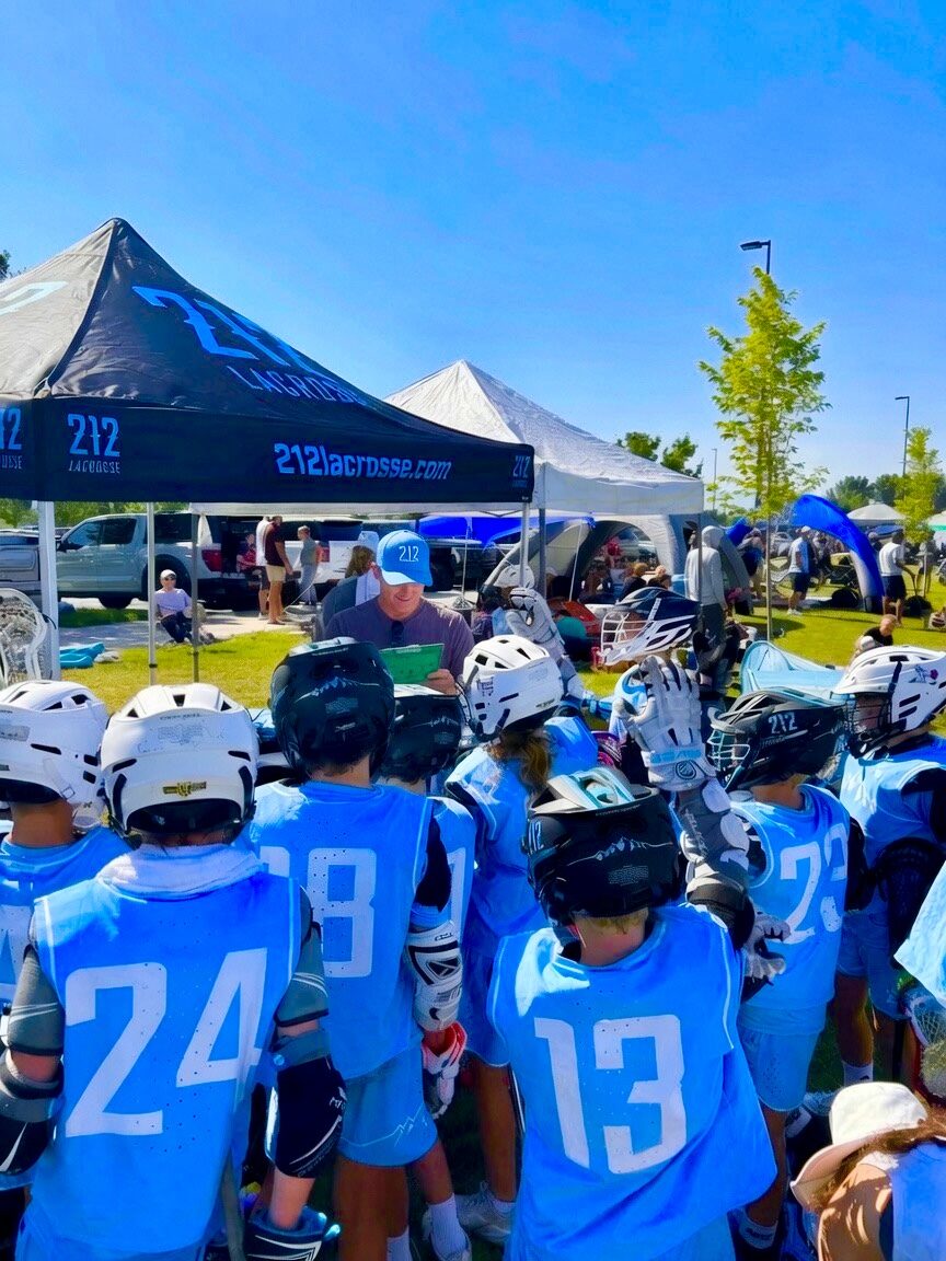 212 Lacrosse coach talking through the game plan with players at the 212 tent