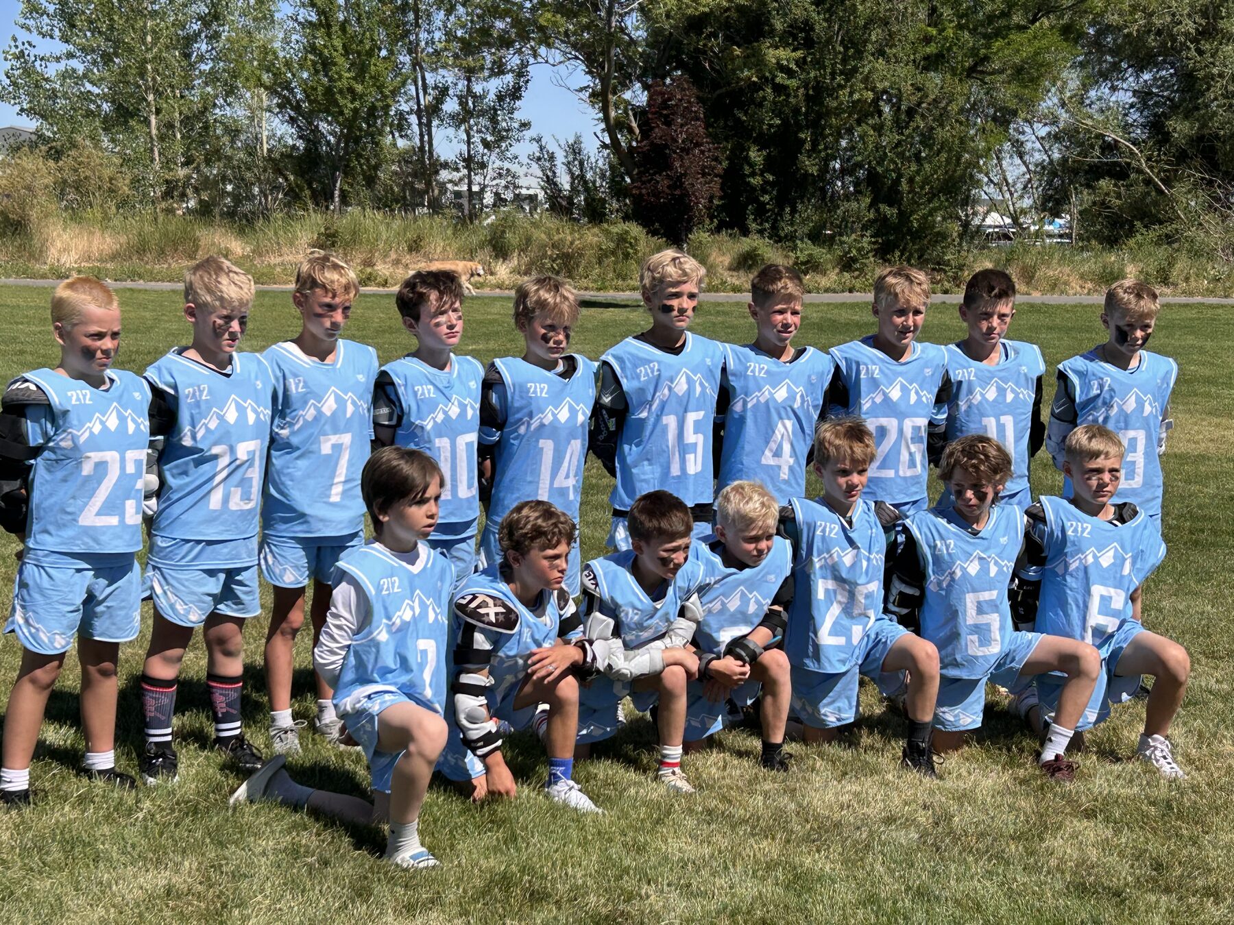 Full 212 Lacrosse youth team posed together in light blue uniforms on the field