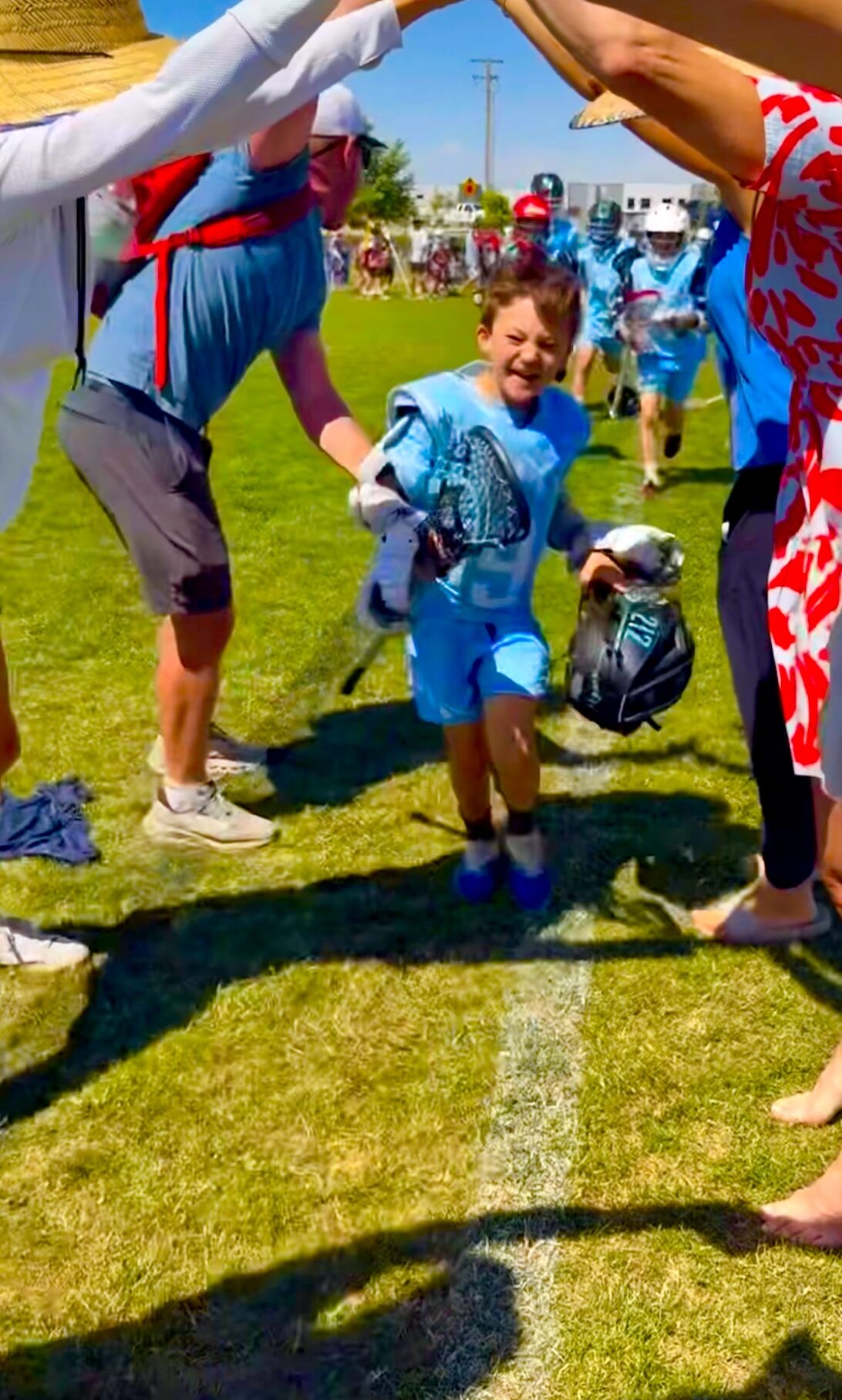 212 Lacrosse player running onto the field through a tunnel of high-fiving parents
